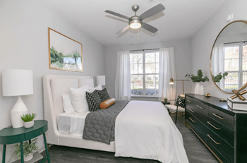 A bedroom with a white bed, a green side table, and a ceiling fan at Deerfield Village, Alpharetta, 30004